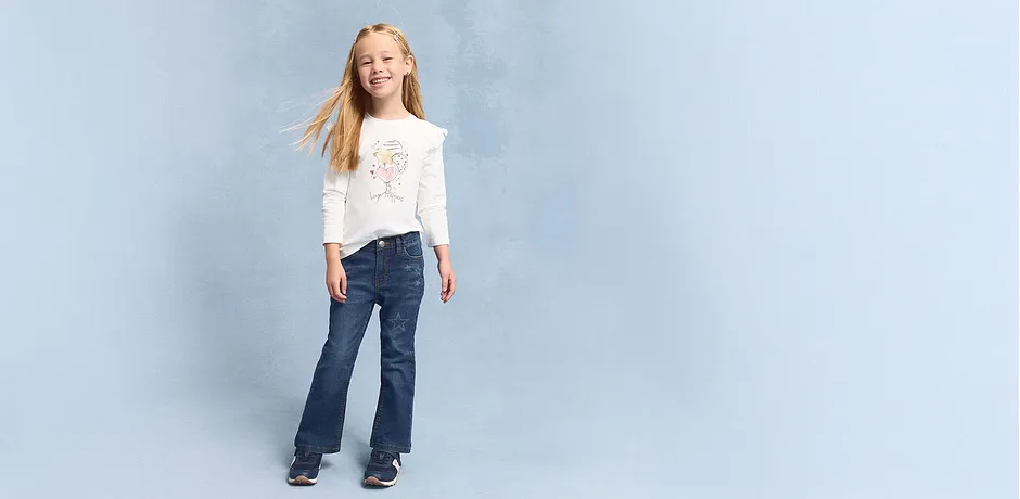 Ležérní look s bílým tričkem s dlouhým rukávem a rozšiřujícími se džínami. 