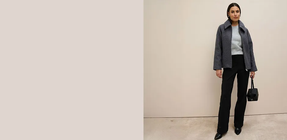 Šedá bunda, šedý svetr a černé kalhoty.