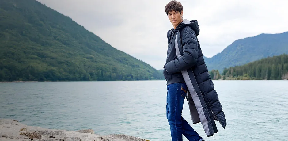 Teplá péřová bunda a džíny chrání před chladem.