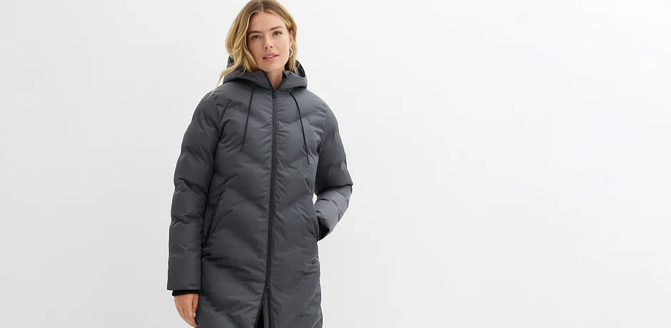 Dlouhý šedý zimní kabát s kapucí a zipem.