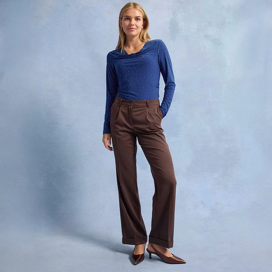 Modré tričko s dlouhým rukávem a puntíky, hnědé kalhoty se širokými nohavicemi a špičaté hnědé boty.