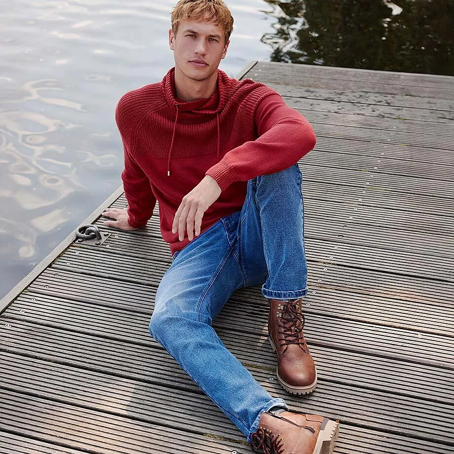 Červen&aacute; mikina s kapuc&iacute; v kombinaci s modr&yacute;mi dž&iacute;ny a hněd&yacute;mi kožen&yacute;mi botami.