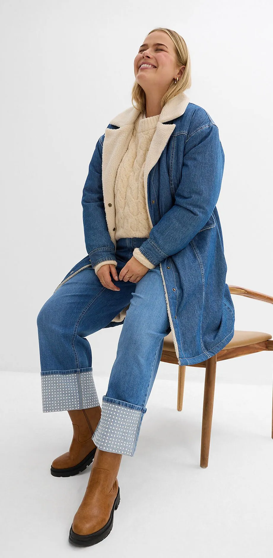 Dž&iacute;nov&yacute; look s dlouh&yacute;m kab&aacute;tem, b&eacute;žov&yacute;m svetrem a dž&iacute;nami.