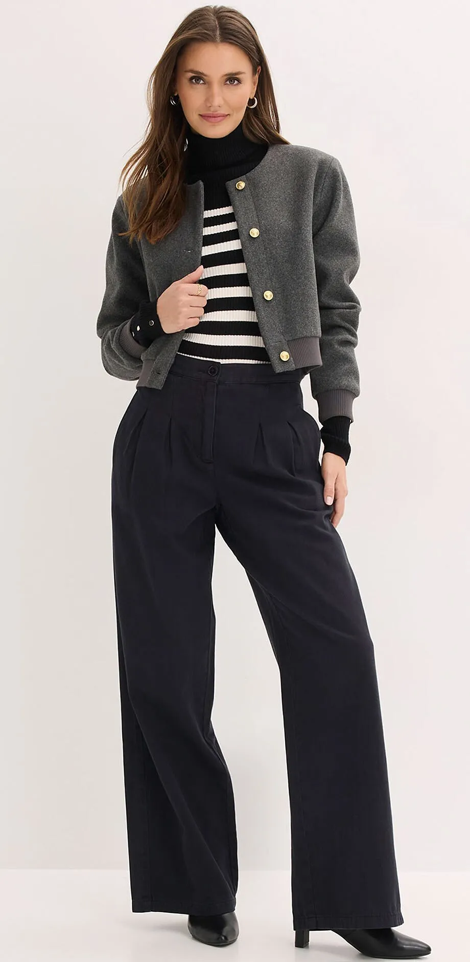 &Scaron;ed&aacute; bunda, pruhovan&yacute; svetr a &scaron;irok&eacute; čern&eacute; kalhoty.