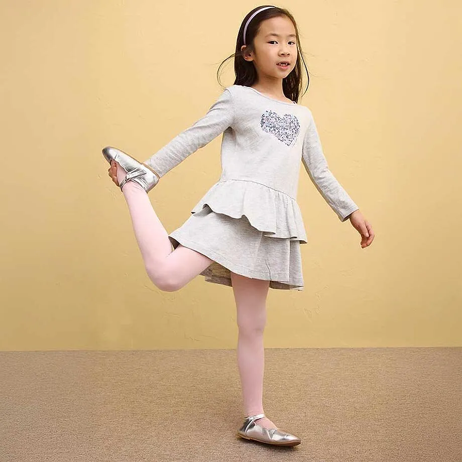 D&iacute;vka m&aacute; na sobě &scaron;ed&eacute; &scaron;aty s vol&aacute;nky a růžov&eacute; leg&iacute;ny.