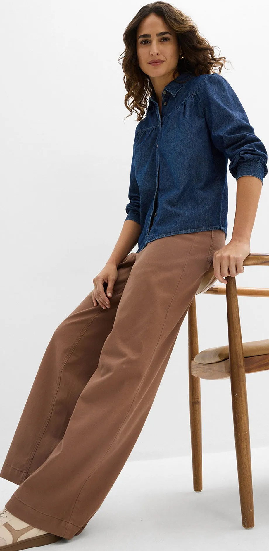 Tmavě modr&aacute; dž&iacute;nov&aacute; ko&scaron;ile v kombinaci s hněd&yacute;mi kalhotami a světl&yacute;mi teniskami.