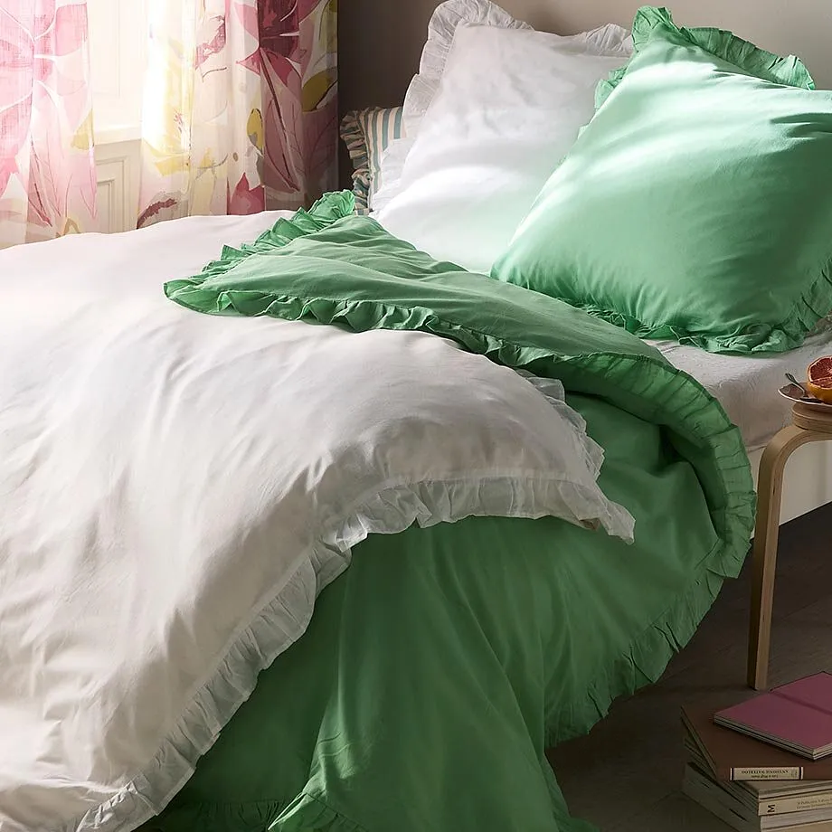 Bettw&auml;sche in Wei&szlig; und Gr&uuml;n schm&uuml;ckt das gem&uuml;tliche Bett.